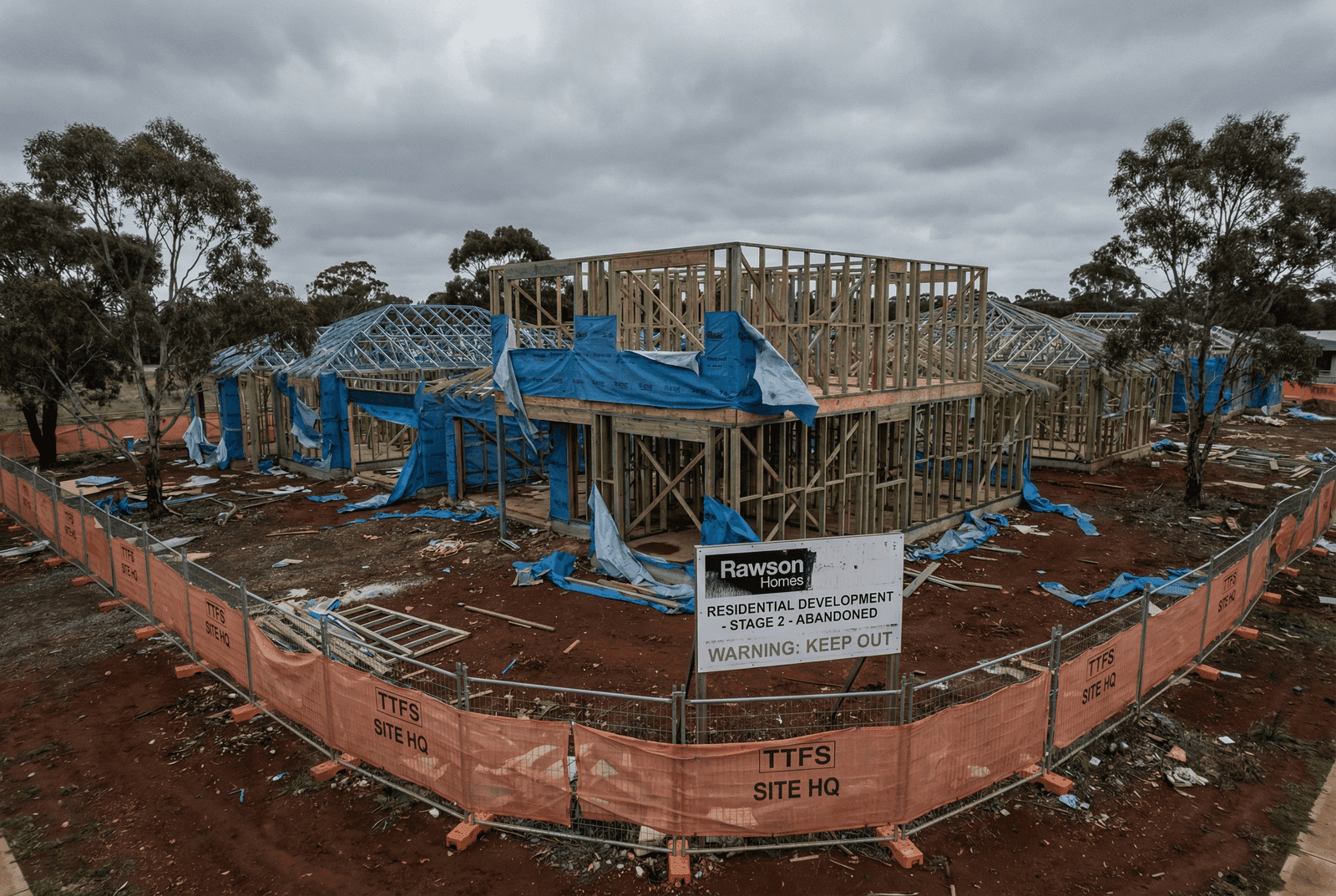 Abandoned Australian residential construction site with incomplete timber-framed houses and no workers