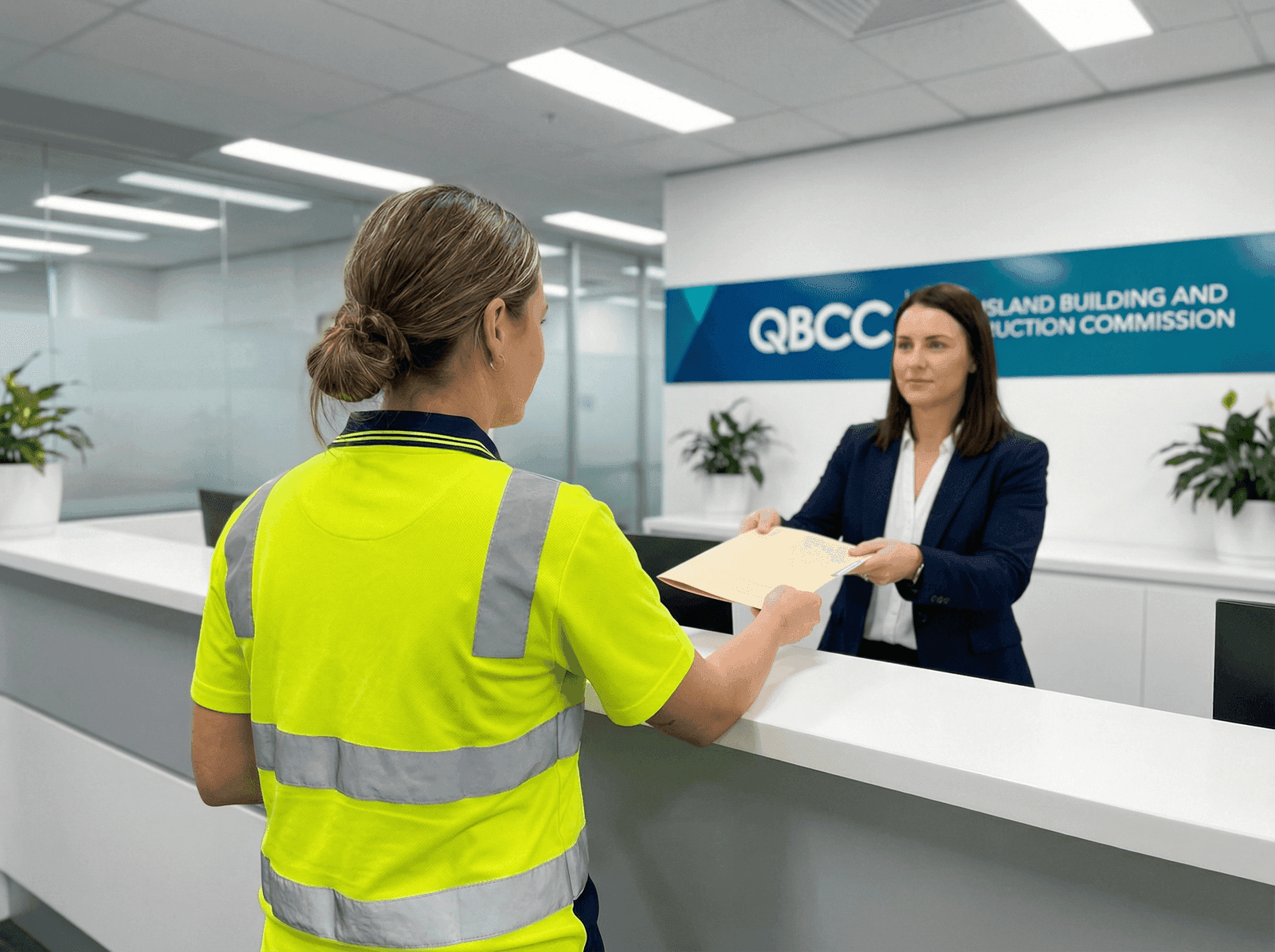 Builder submitting QBCC licence application documents at a government service counter